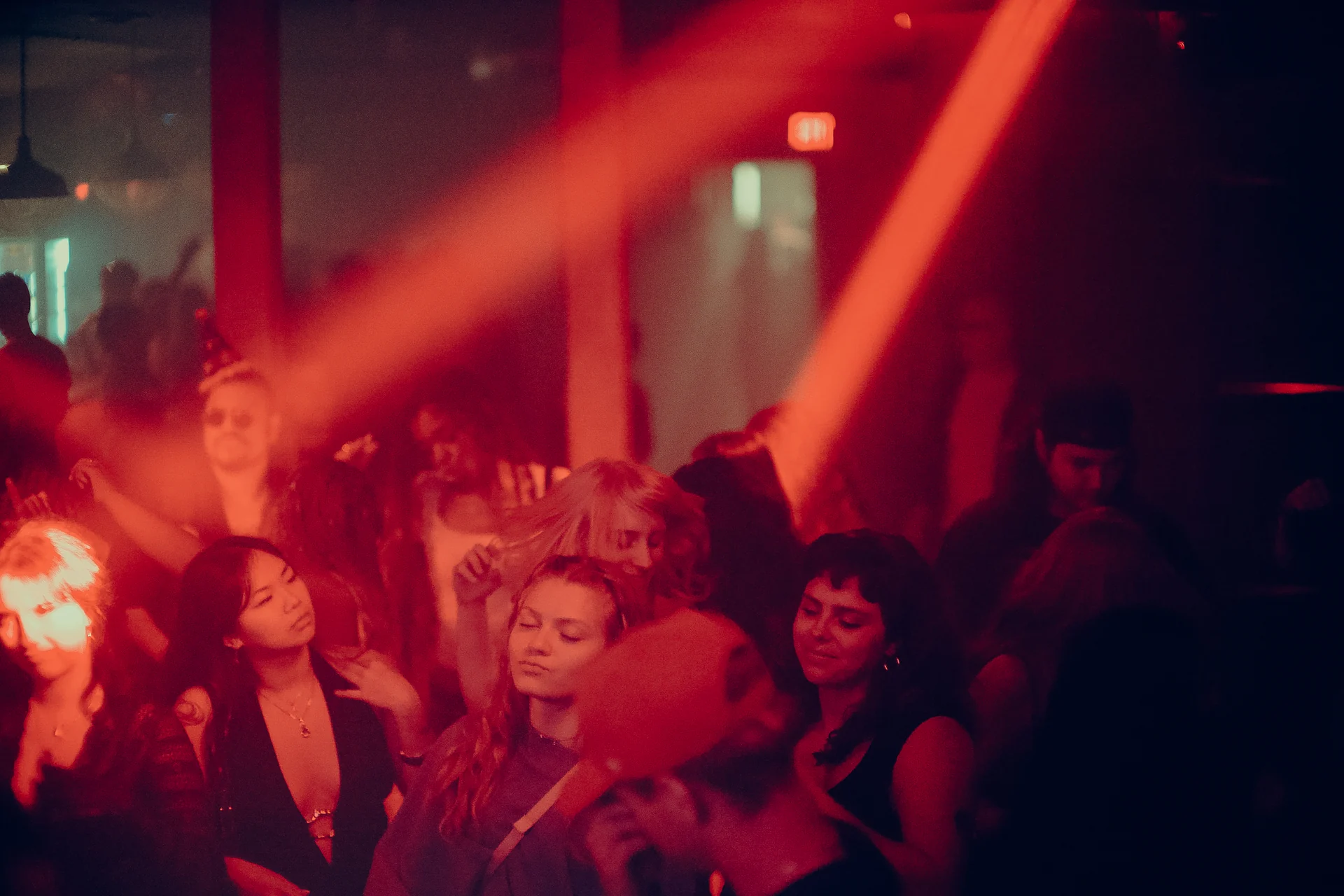 Raised hands fill the dancefloor as red light sweeps across the crowd.