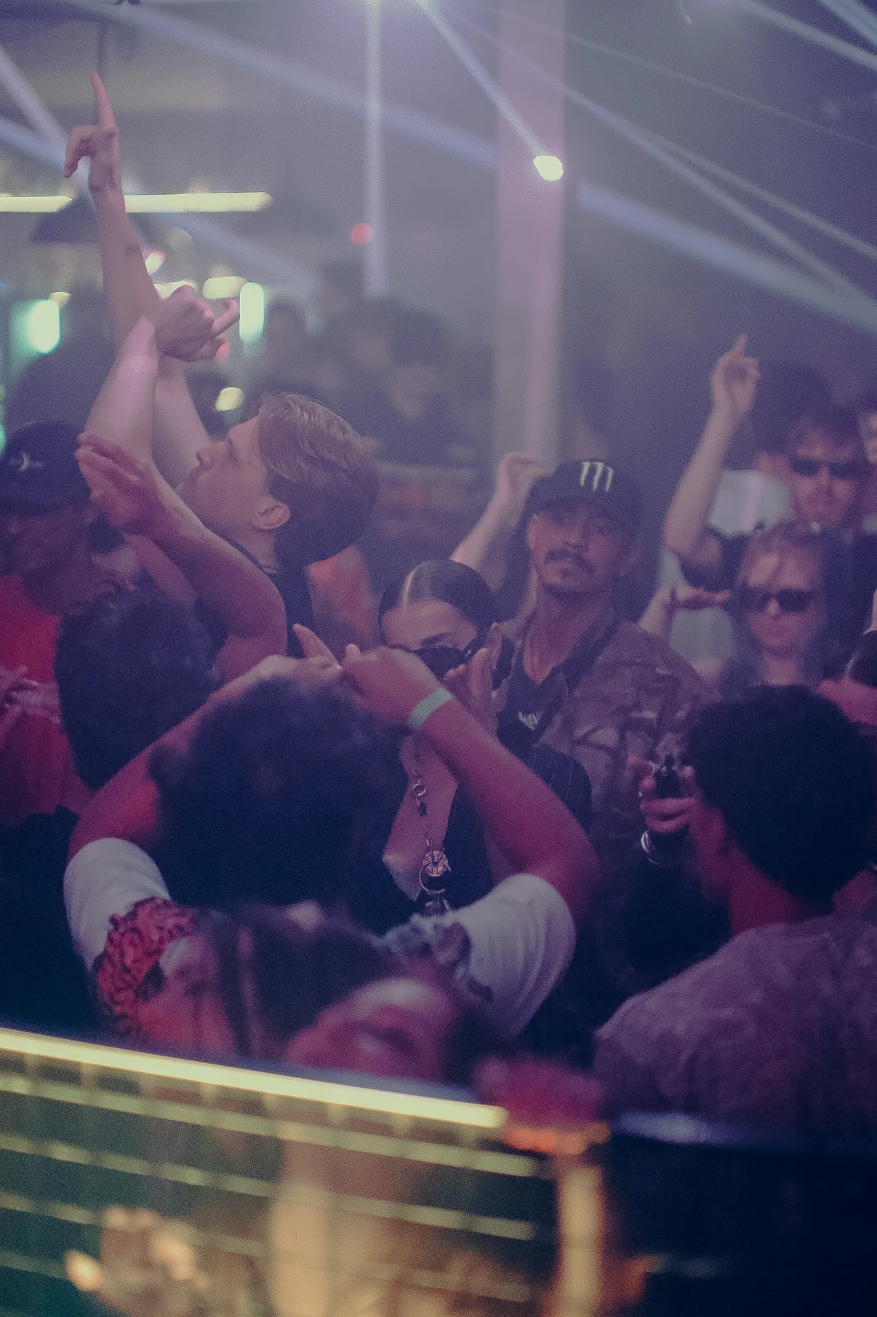 Dancers crowd together under narrow white beams reaching across the room.