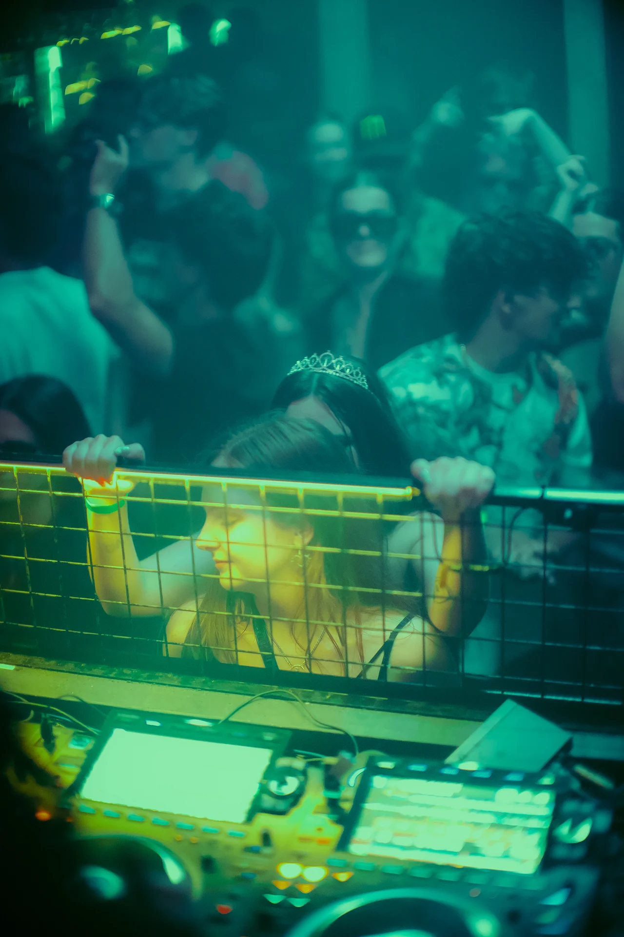 Hands rise beyond the mixer as turquoise light washes over the front row.