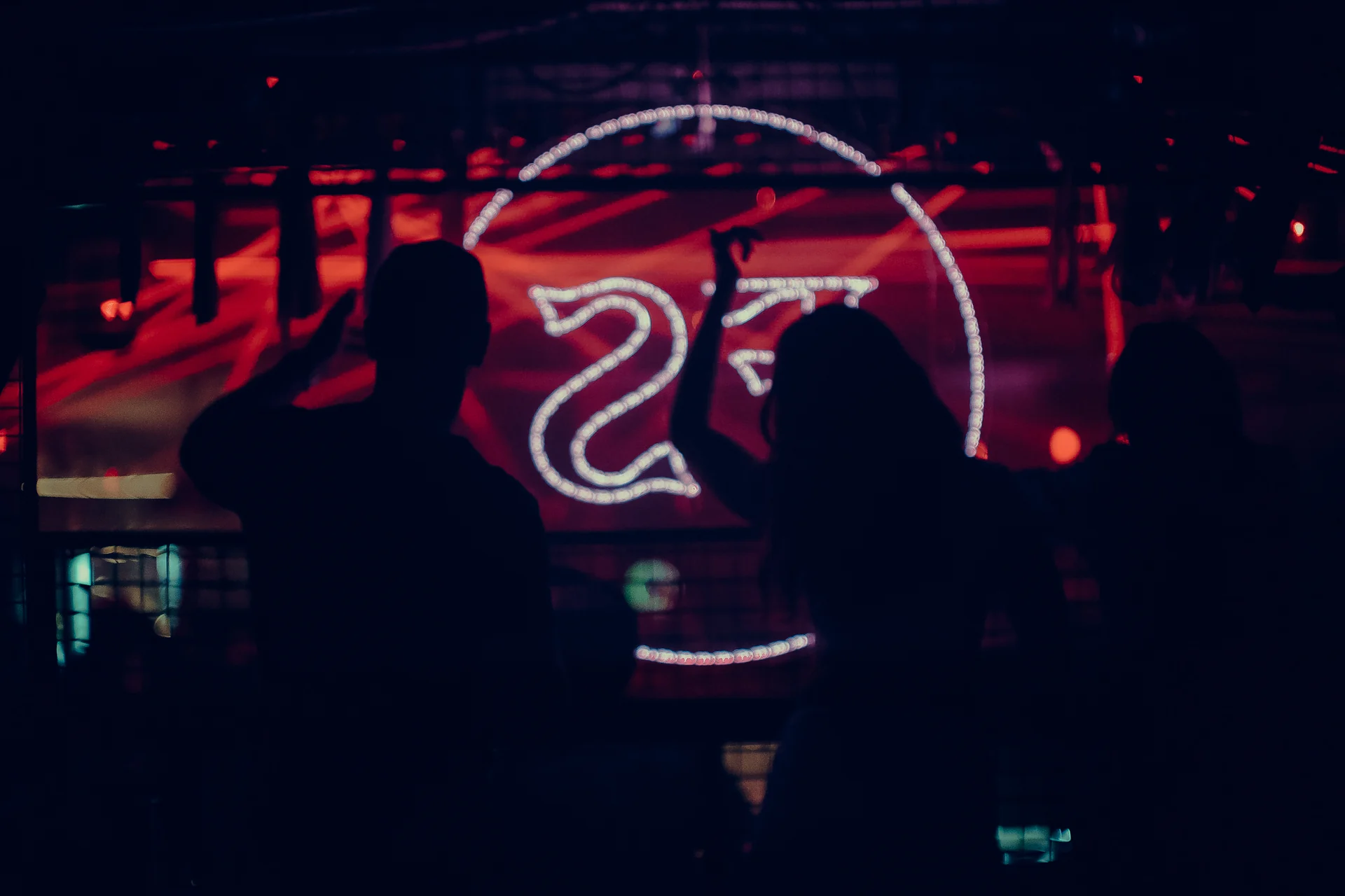 A DJ is silhouetted against the Frequency Shift roundel and horizontal red lasers.