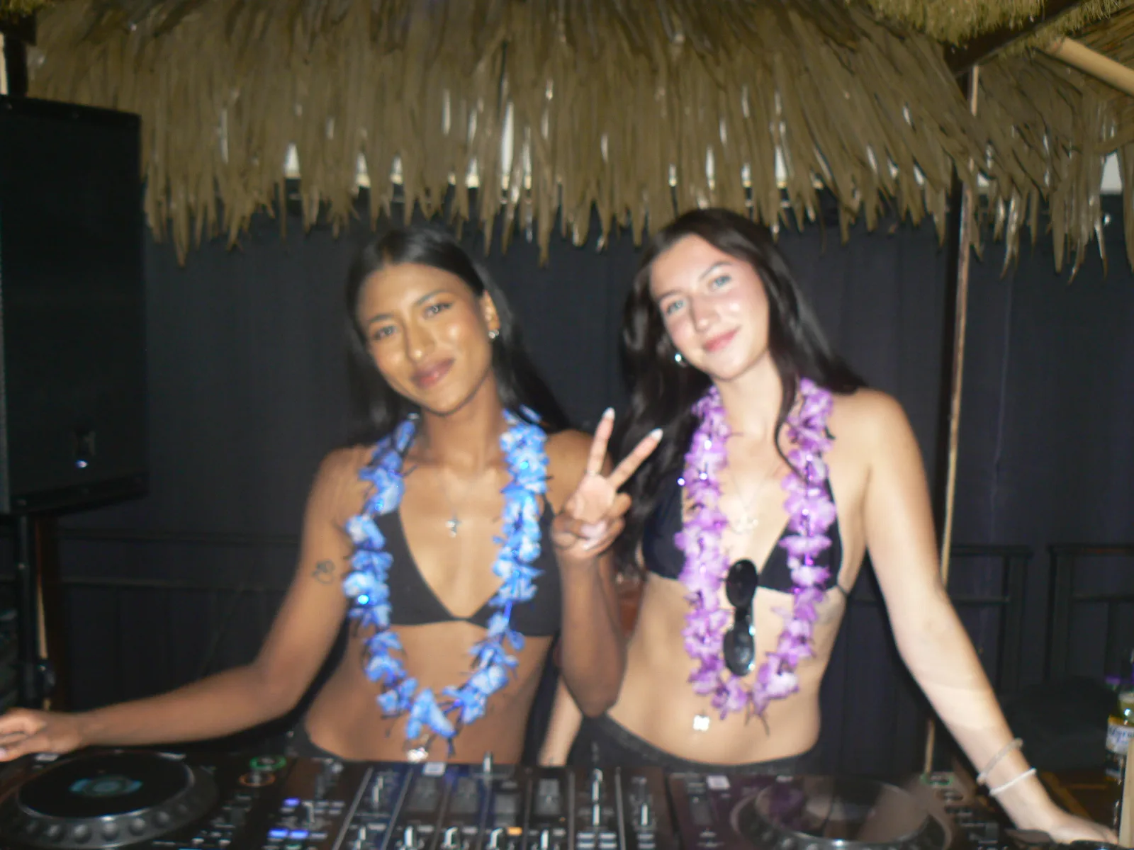 A dance floor and DJ booth cut through by violet laser beams.